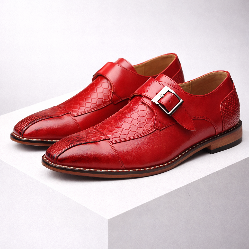 Red leather monk strap dress shoes with silver buckle and crocodile embossed texture detail on white display block