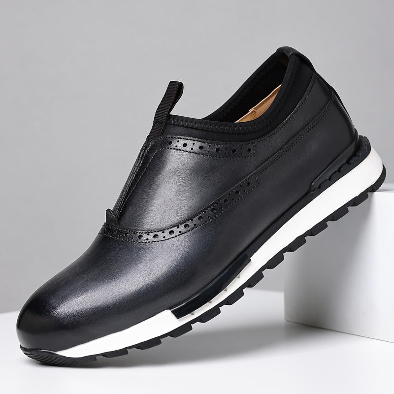 Black men's leather slip-on loafers with brogue detailing and white rubber sole on gray background