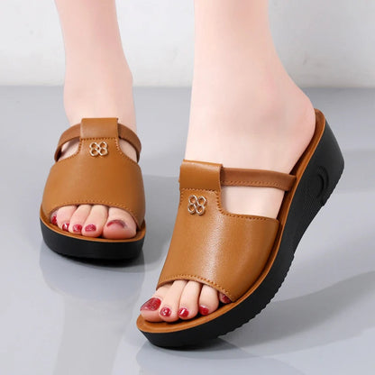 Women's brown leather platform slide sandals with cutout detail and floral accent, open toe, black sole.
