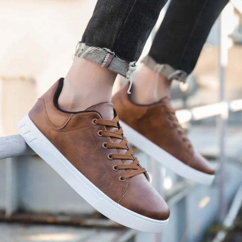 Men's brown leather lace-up sneakers with white sole worn with black distressed jeans
