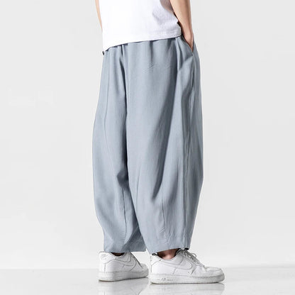 Men's wide-leg light blue cotton drawstring pants paired with white sneakers and white t-shirt, relaxed fit style