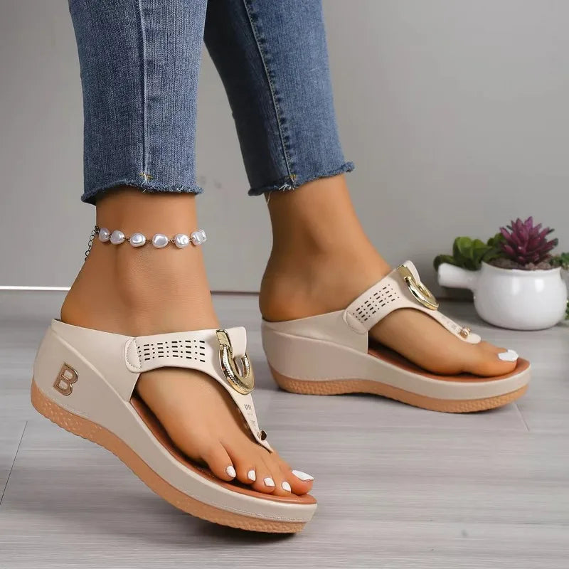 Beige wedge flip-flop sandals with gold hardware and letter B detail, worn with jeans and pearl anklet