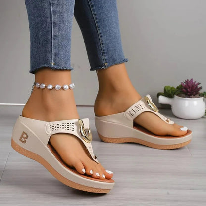 Beige wedge flip-flop sandals with gold hardware and letter B detail, worn with jeans and pearl anklet