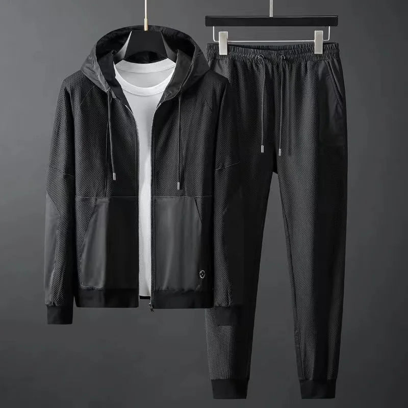 Men's black hooded zip-up tracksuit set with mesh panels, featuring matching jogger pants with elastic waistband.