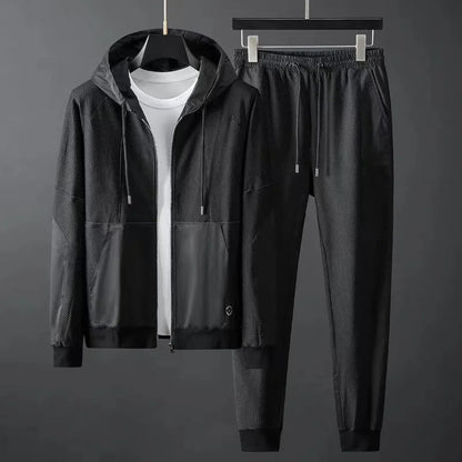 Men's black hooded zip-up tracksuit set with mesh panels, featuring matching jogger pants with elastic waistband.