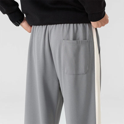 Back view of men's gray wide-leg sweatpants with white side stripe, elastic waistband, and back patch pocket.