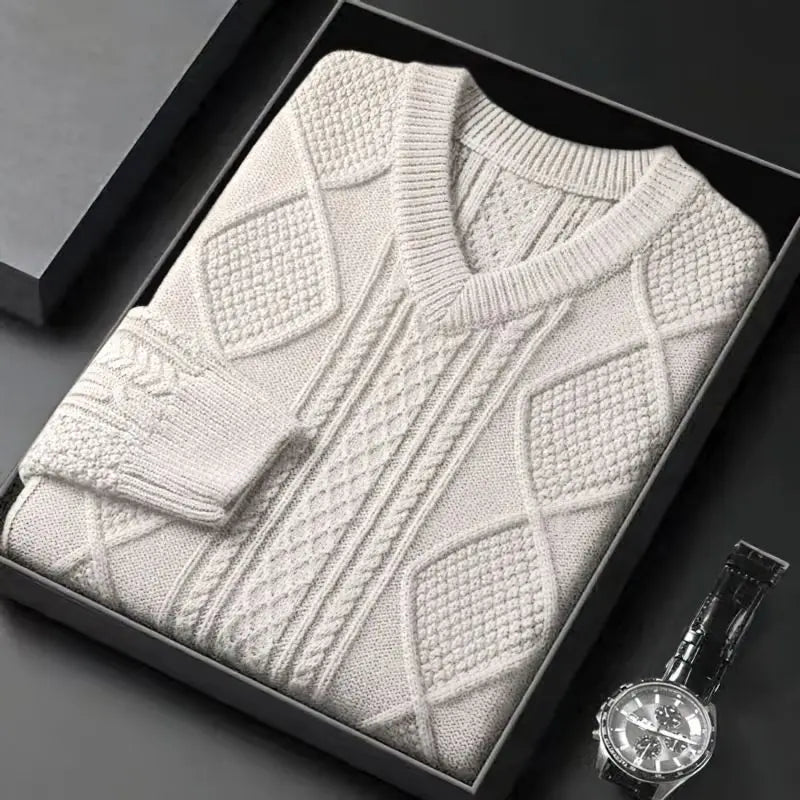 Cream cable knit v-neck wool sweater folded in black gift box beside a luxury watch