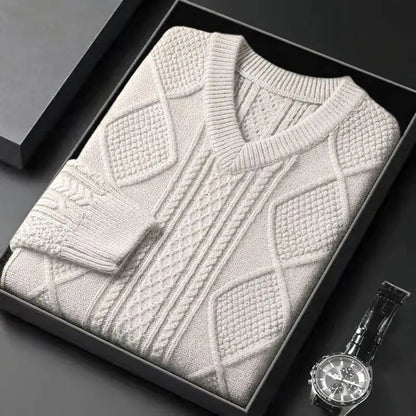 Cream cable knit v-neck wool sweater folded in black gift box beside a luxury watch