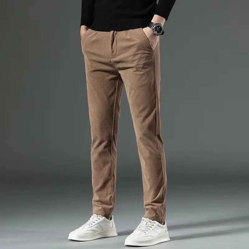 Men's slim fit khaki corduroy chino pants paired with black sweater and white sneakers, shown from waist down