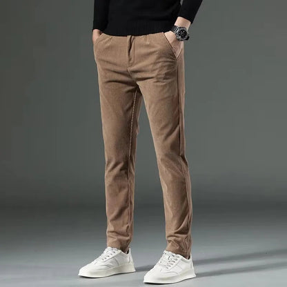 Men's slim fit khaki corduroy chino pants paired with black sweater and white sneakers, shown from waist down