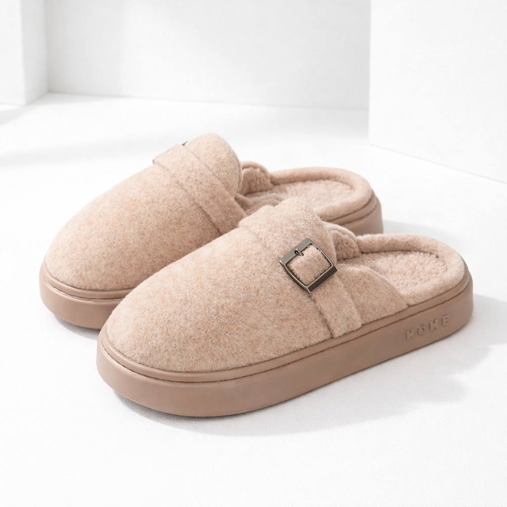 Cozy beige plush slip-on mule slippers with metal buckle detail and thick rubber sole, labeled HOME